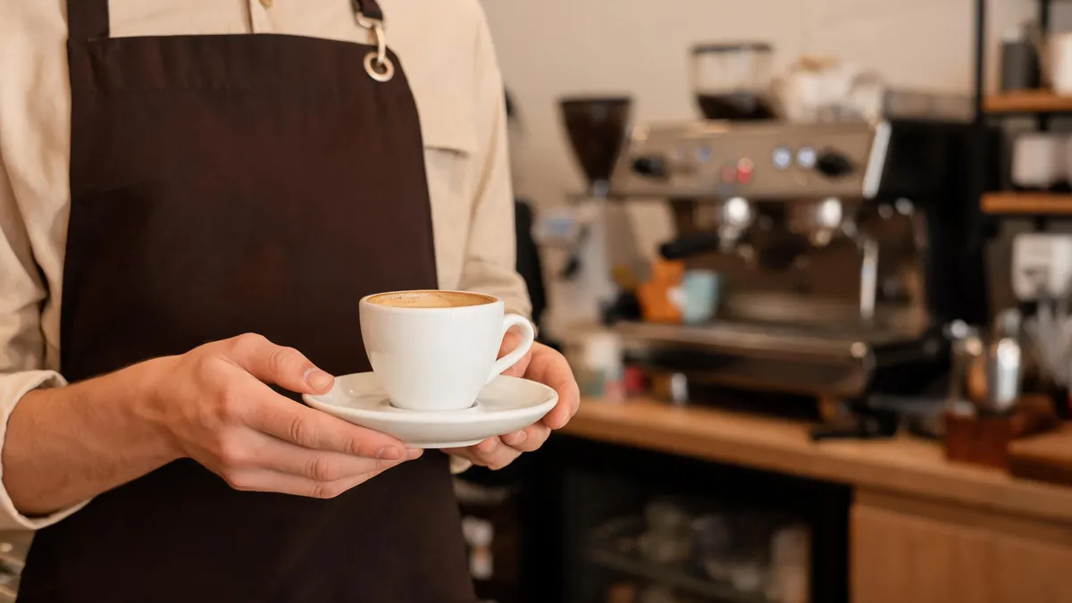 Cafe counter with stacked ceramic mugs, serving plates and a cake stand